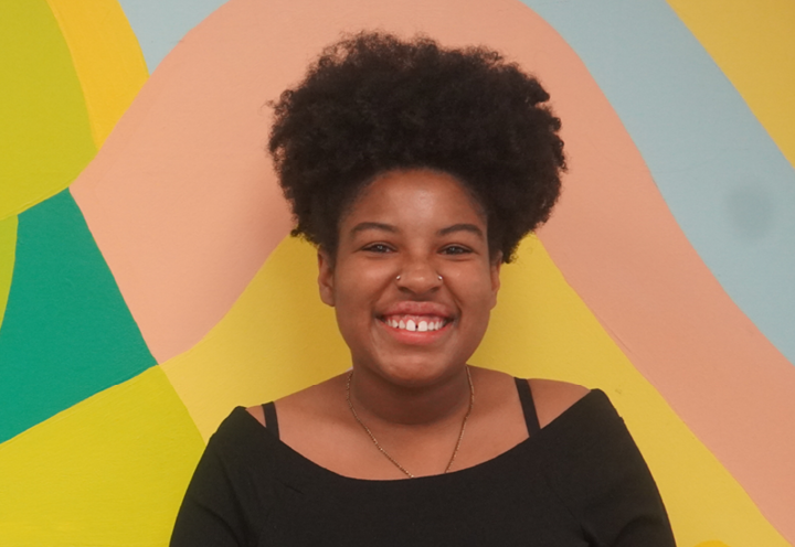 smiling young woman standing against colourful mural