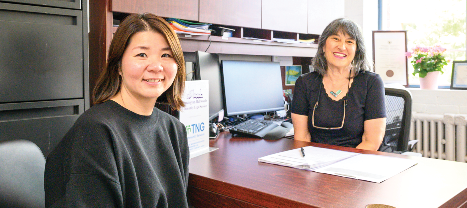 smiling woman sitting at desk with lawyer