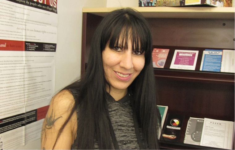 smiling woman in front of a shelf with brochures