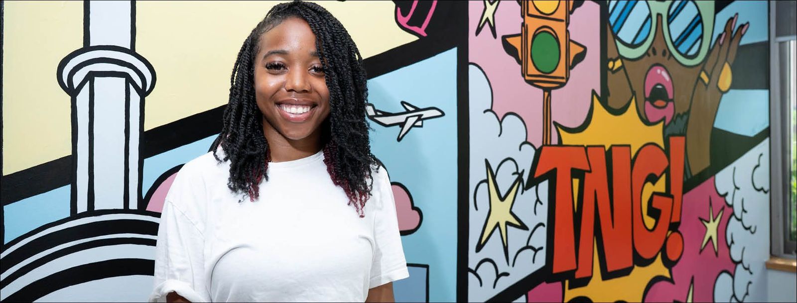 smiling teenaged girl standing in front of mural