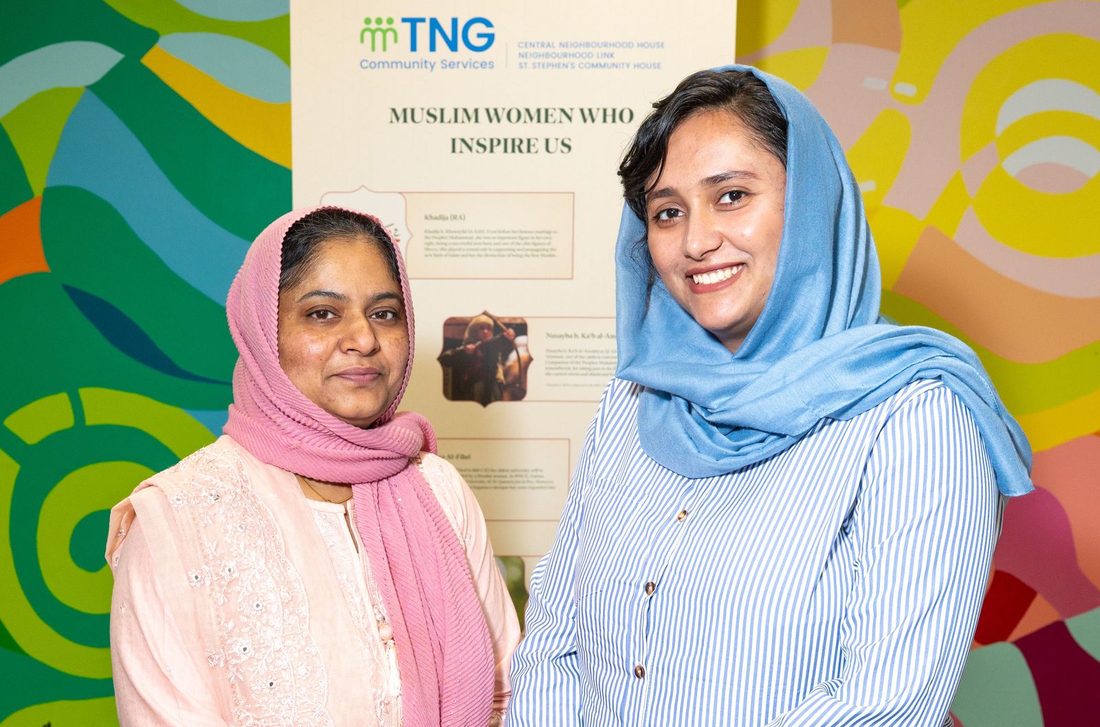 two women standing in front of a sign with the title "Muslim Women who Inspire us"