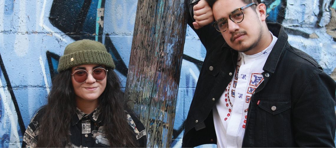 youth standing against blue wall with graffiti