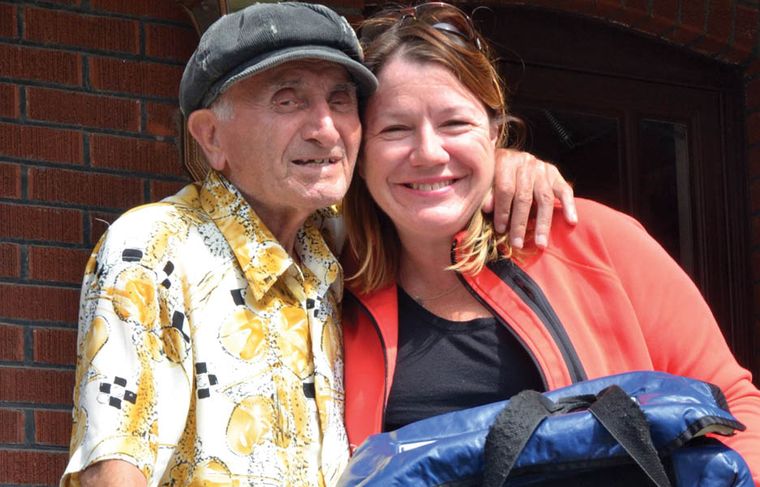 elderly man hugging woman bring holding a meal bag