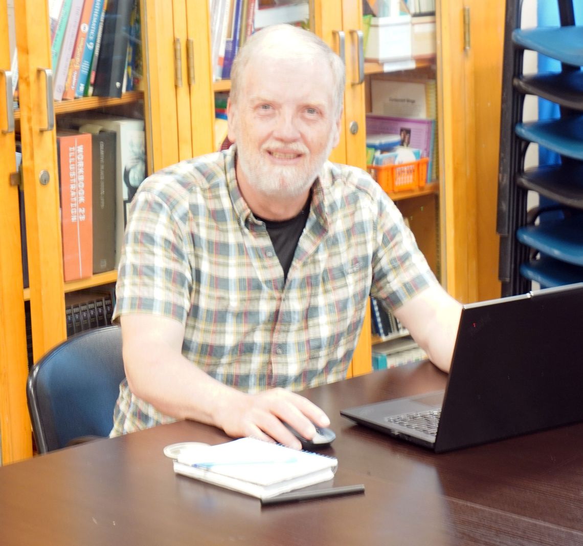smiling man sitting at table with a laptop