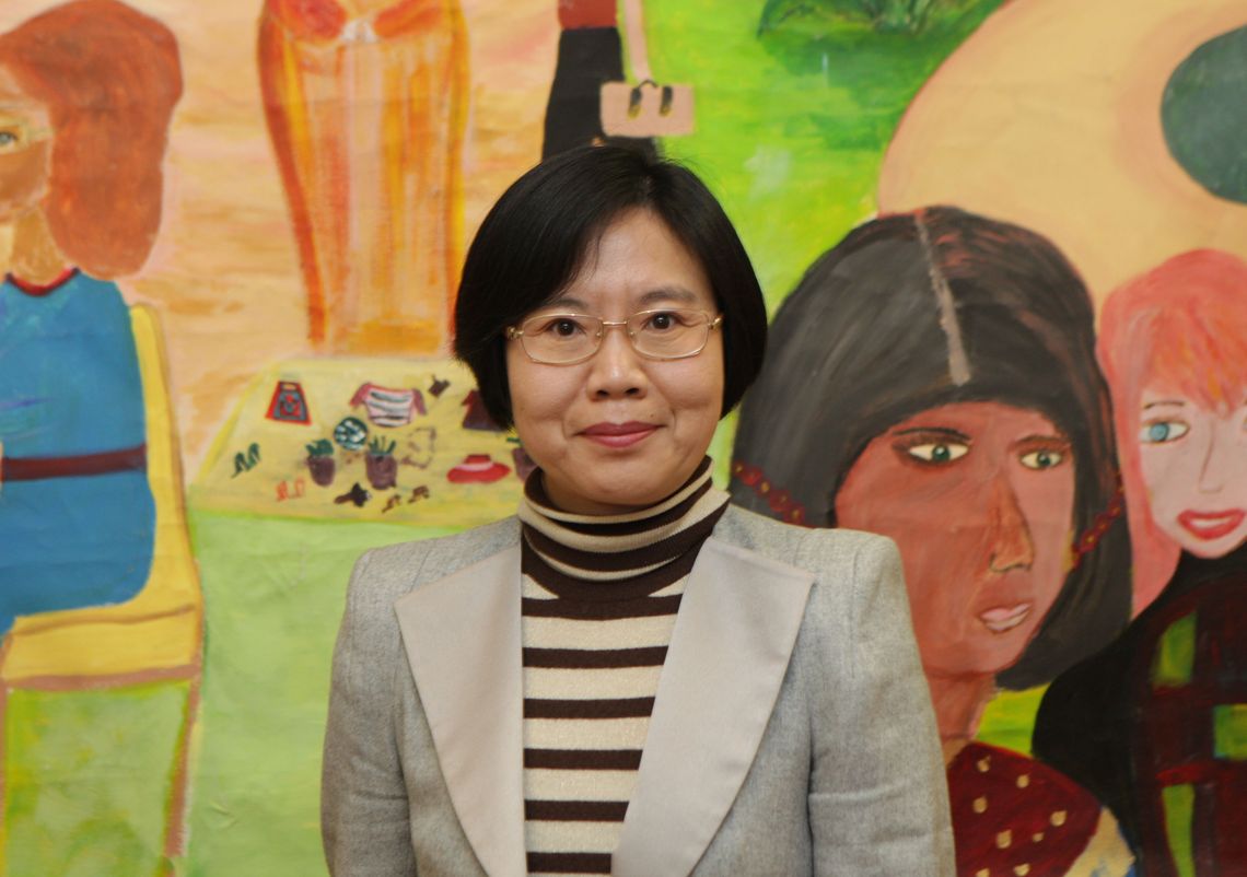 middle aged woman standing in front of c colourful mural