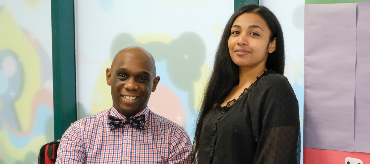 teacher sitting down with young woman standing