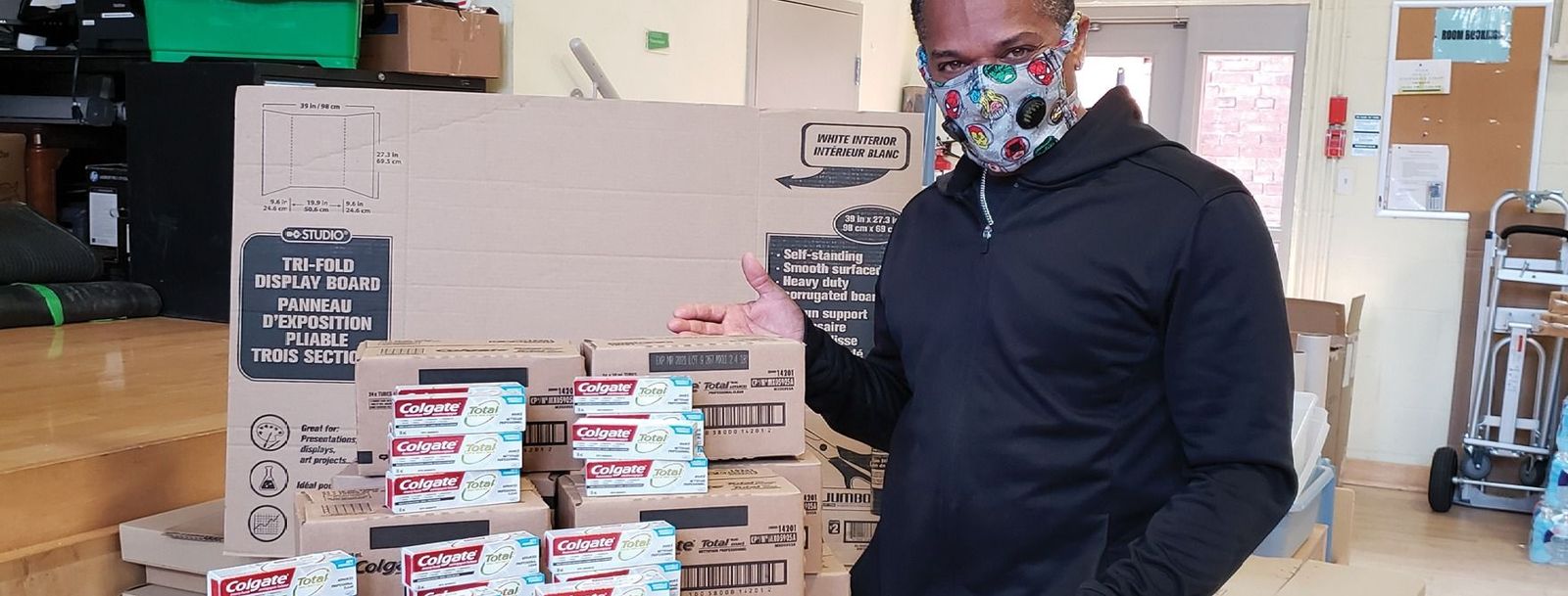 man standing beside donations of toothpaste