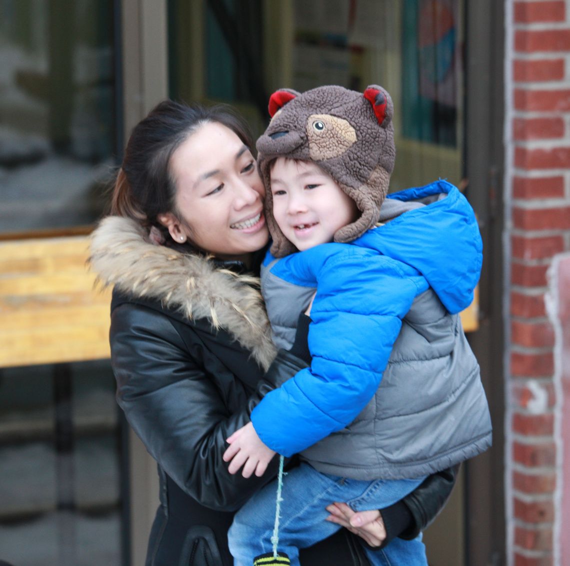 woman holding young child exiting door