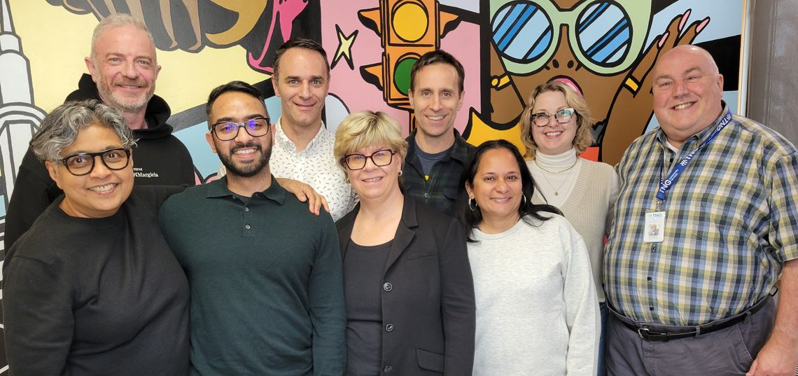 Board members standing in front of a colourful mural