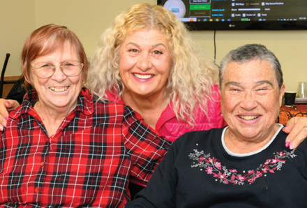 personal support worker hugging two seniors