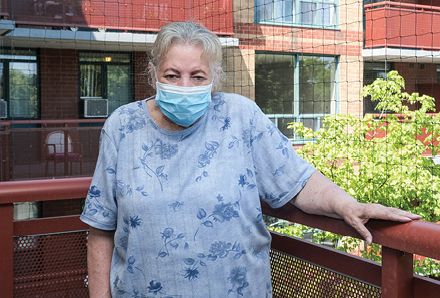 elderly woman standing on balcony