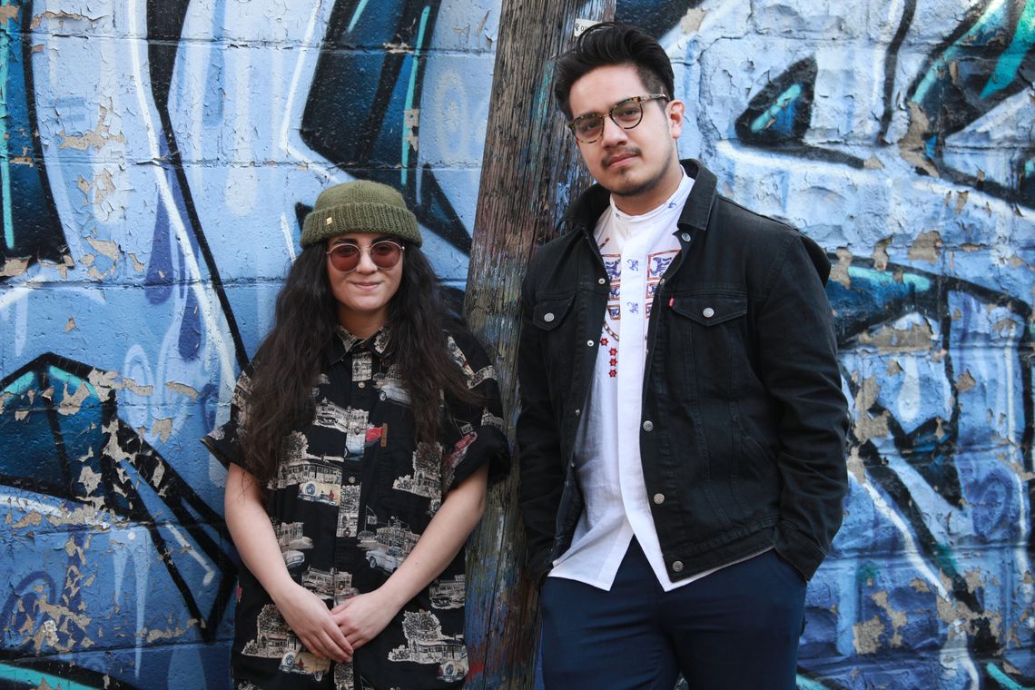 young woman and man standing against a graffiti wall