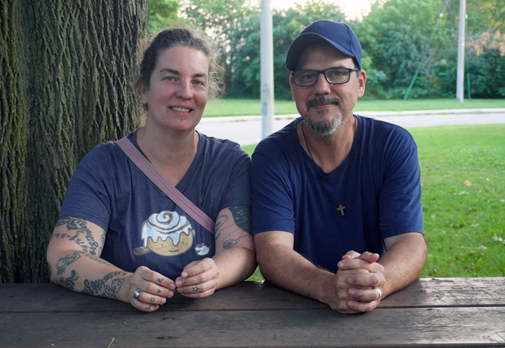 man and woman sitting at a picnic table in the park