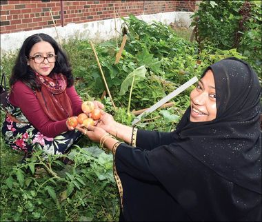 two women holding vegetables in a garden